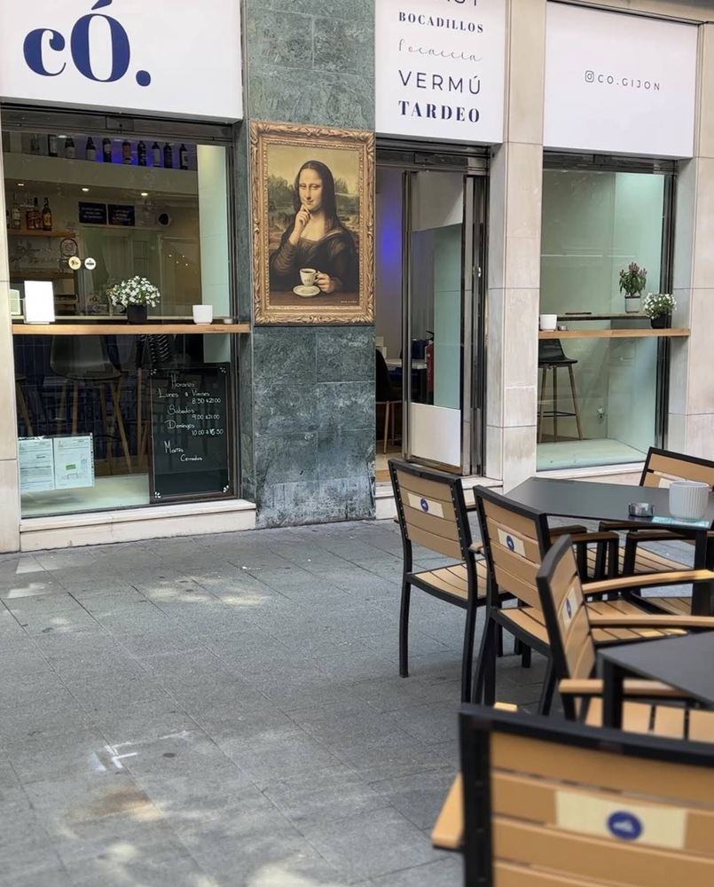 Terraza de có. en la Calle Langreo de Gijón, con la fachada azul y el cuadro de la Mona Lisa