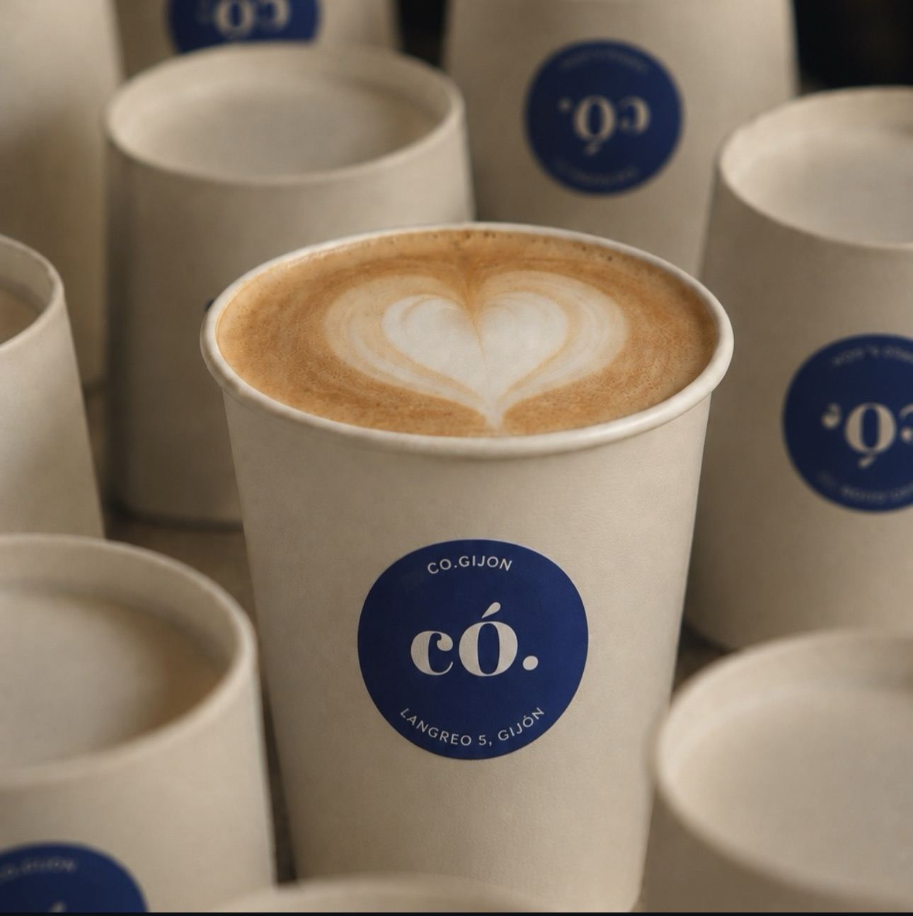 Latte con corazón dibujado en la espuma, servido en taza de có.