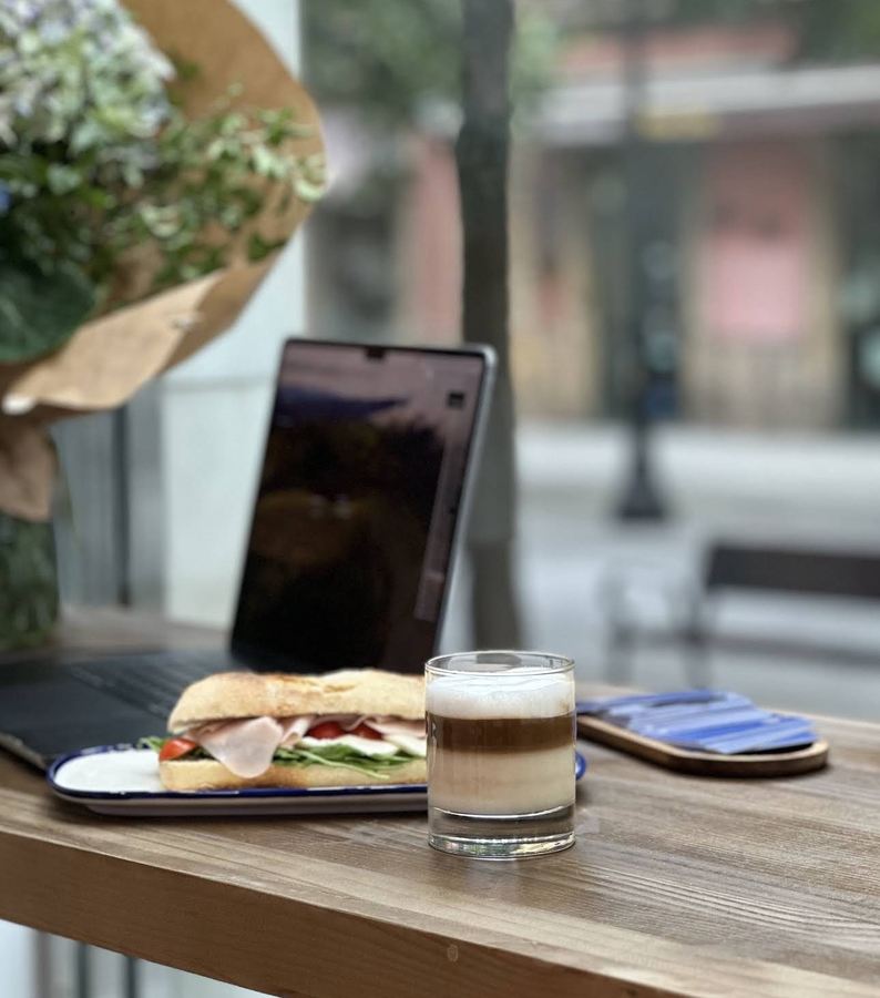 Mesa junto al ventanal, con bocadillo y café en vaso